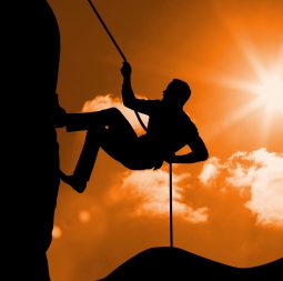 Digital composition of silhouette man climbing a mountain against sunny background